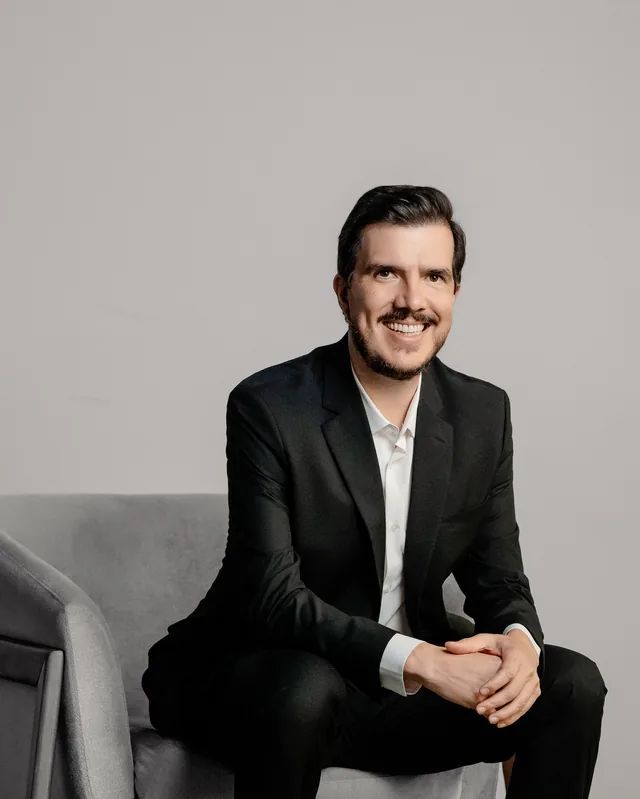 Bruno Gimenes sentado numa poltrona, sorrindo